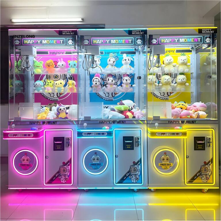 Tres máquinas de garra adyacentes "MOMENTO FELIZ" (rosa, azul, amarilla) llenas de juguetes de peluche bajo una iluminación de neón.