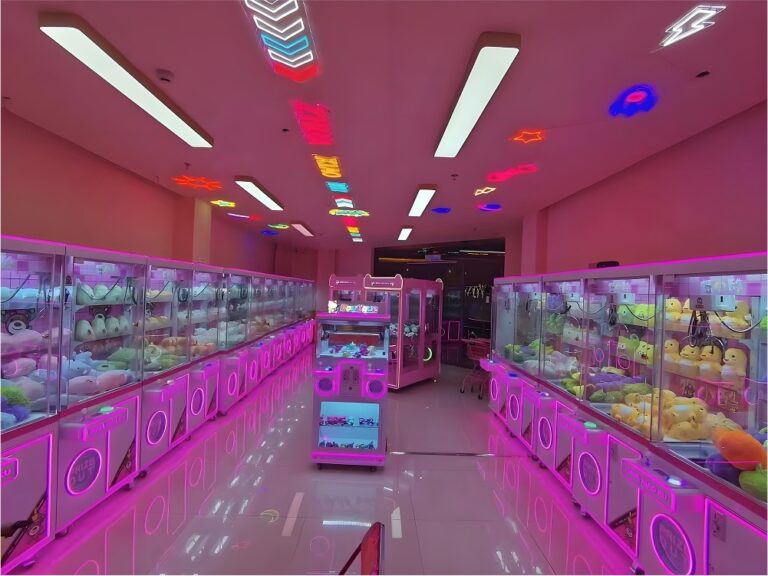 Largo pasillo de máquinas de garra instaladas bajo una iluminación de neón rosa, que muestra un diseño de arcade de alta capacidad y filas de gabinetes llenos de peluches.